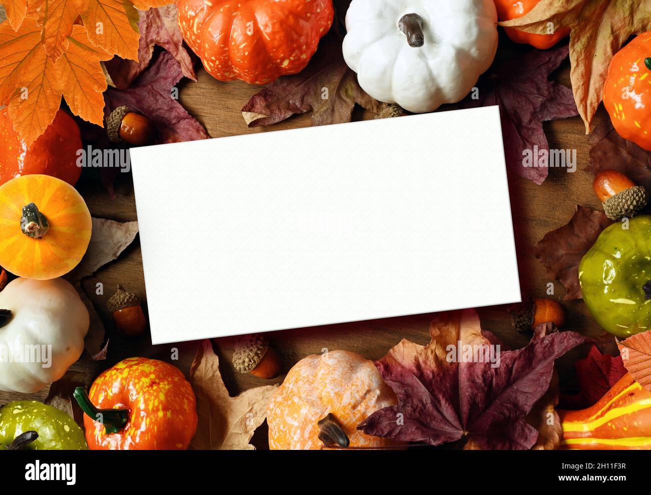 Kreatives Muster, Herbsthintergrund. Orangefarbener Kürbis und Blätter auf braunem Holzgrund. Halloween. Karte. Stockfoto