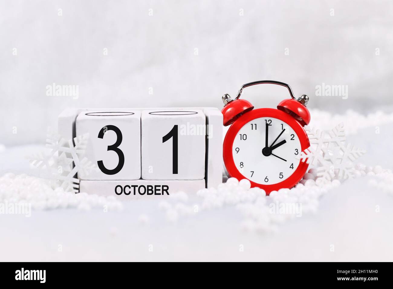 Konzept für den Zeitwechsel für die Sommerzeit im Winter in Europa am 31. Oktober mit rotem Wecker und Kalender im Schnee Stockfoto