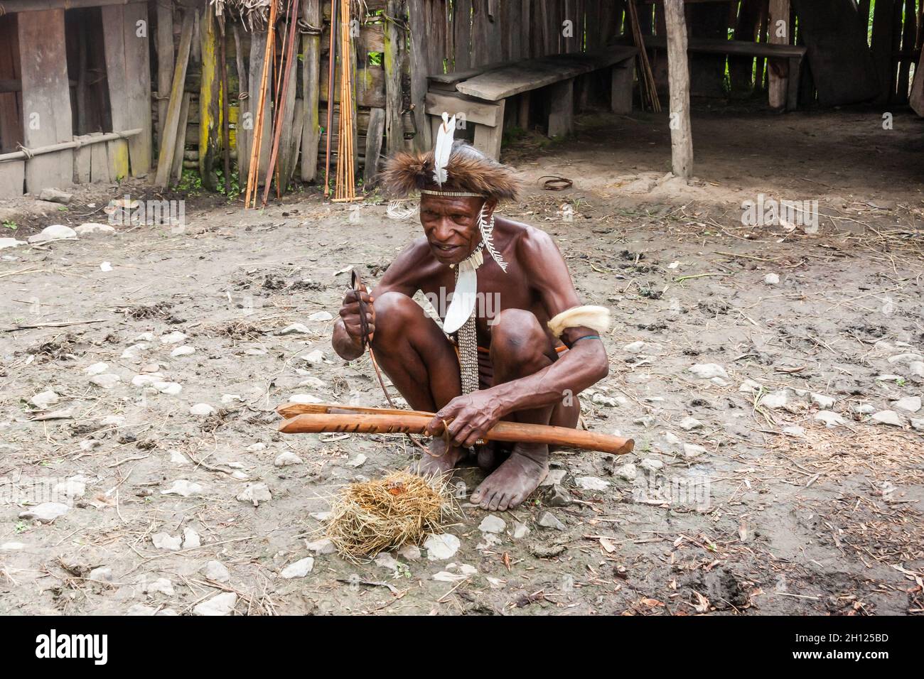 Wamena, Indonesien - 9. Januar 2010: Mann des Dani-Stammes in traditioneller Kleidung entzündet Feuer. Indonesisch-Neuguinea Stockfoto