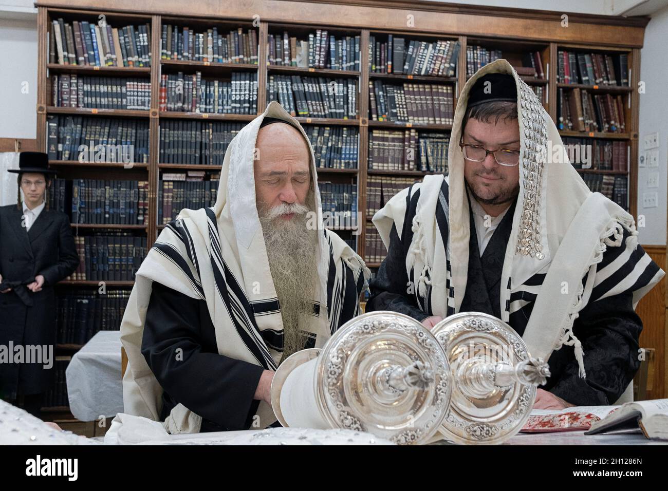 Ein orthodoxer jüdischer Mann rezitiert einen Segen, als er in einer kleinen Synagoge in Williamsburg, Brooklyn, NYC, bei einem Sukkos-Morgengottes zur Torah gerufen wurde. Stockfoto