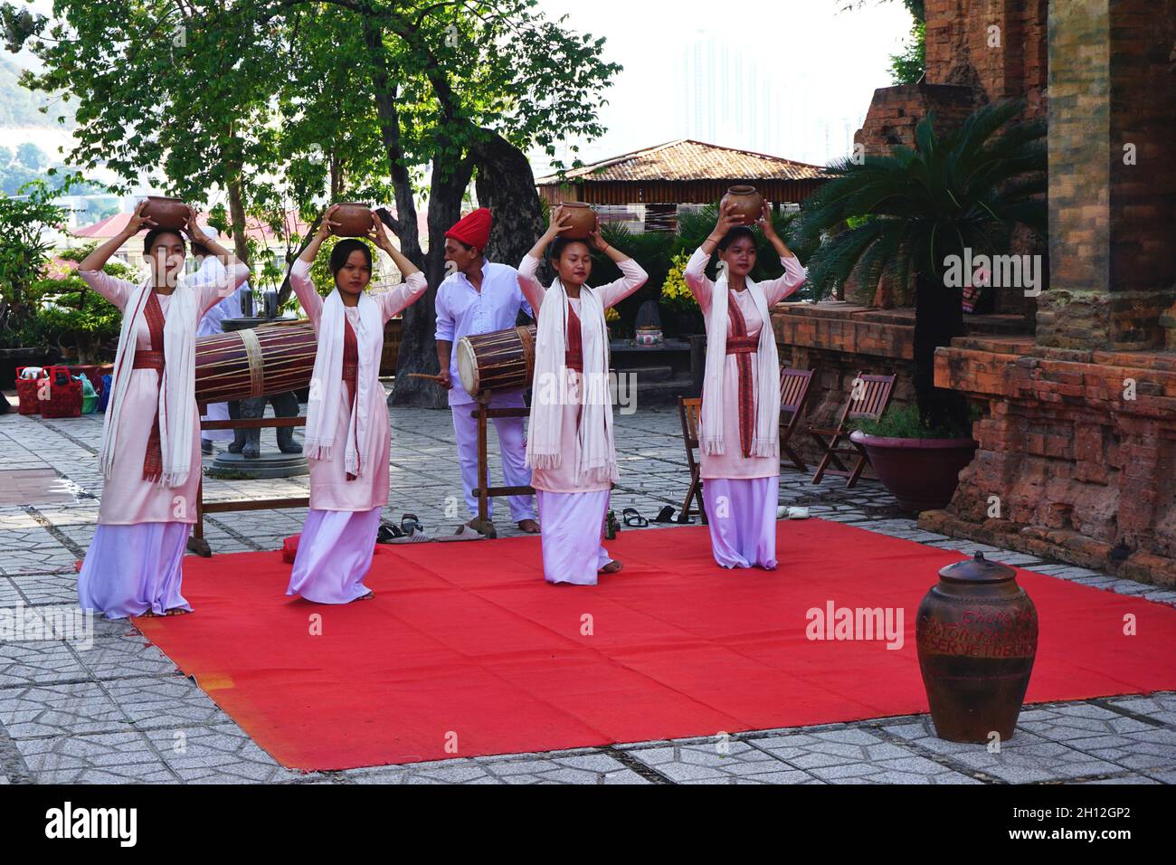 Junge vietnamesische Frauen balancieren Tontöpfe auf ihren Köpfen, während sie einen traditionellen ethnischen Tanz im alten Cham-Tempel, Nha Trang, Vietnam, durchführen. Stockfoto