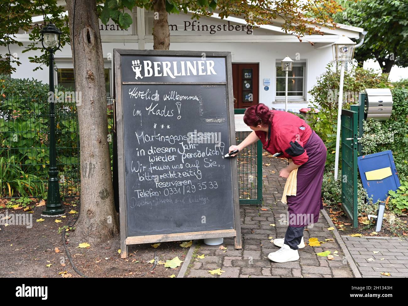 Berlin, Deutschland. Oktober 2021. Eine Tafel im „Kade's Restaurant“ am Pfingstberg macht darauf aufmerksam, dass Reservierungen rechtzeitig vorgenommen werden sollten. Die Mitarbeiterin Claudia Herrmann schreibt dazu die Tafel deutlich sichtbar vor den Eingang. In diesem Jahr können zum Beispiel wieder das Martinmas-Gänseessen und Weihnachtsfeiern für Gäste im Restaurant stattfinden. Quelle: Jens Kalaene/dpa-Zentralbild/dpa/Alamy Live News Stockfoto