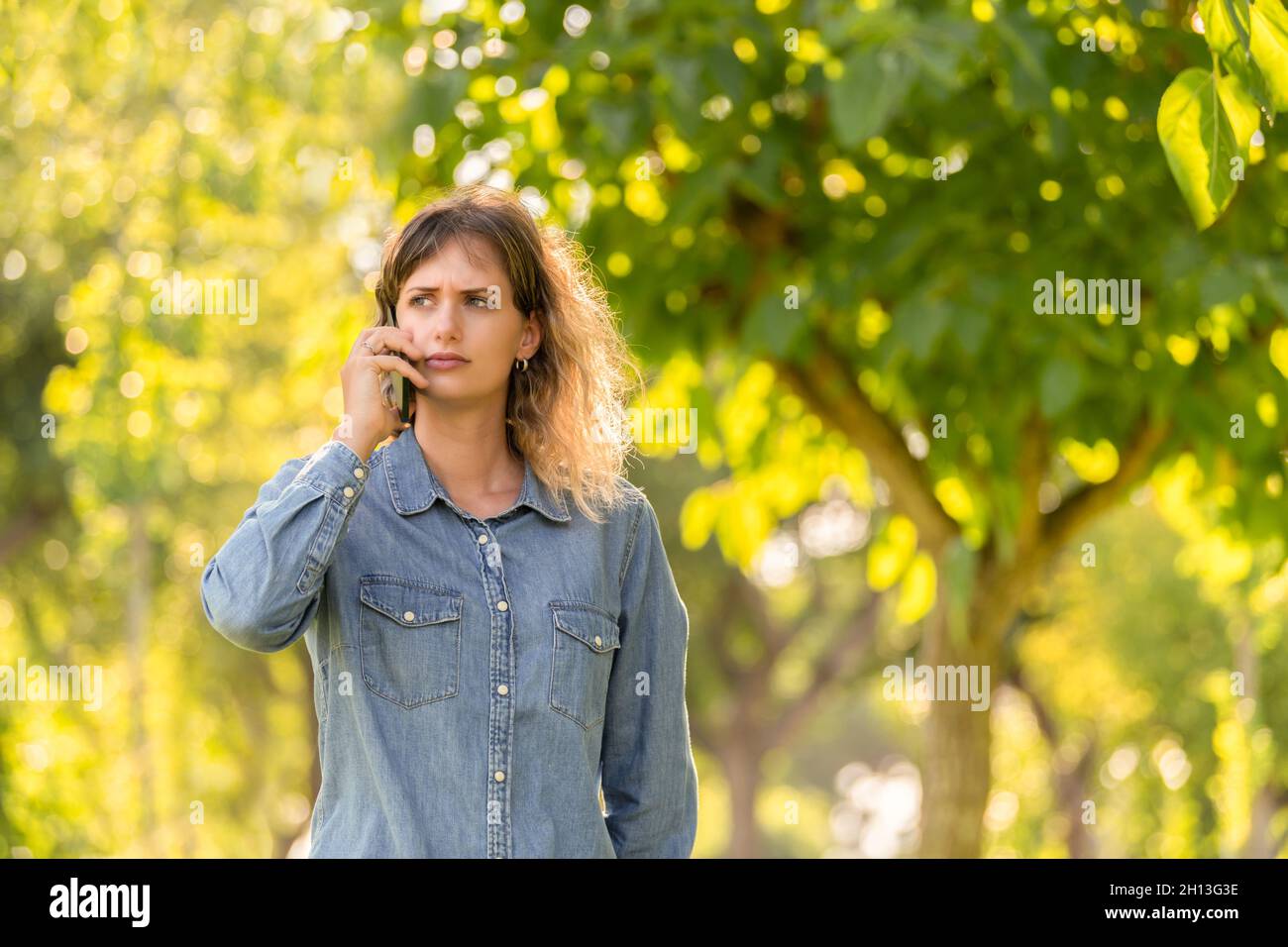 Frau mit Besorgnis Ausdruck im Gespräch mit dem Handy in einem Park Stockfoto
