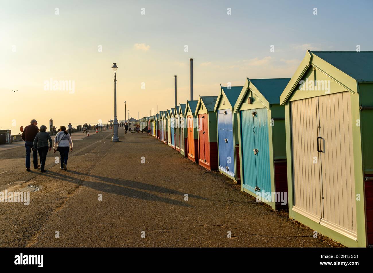 Eine Reihe von bunten Strandhütten, die im weichen, warmen Licht des Oktobernachmittages an der Strandpromenade von Hove, East Sussex, England, glühen. Stockfoto