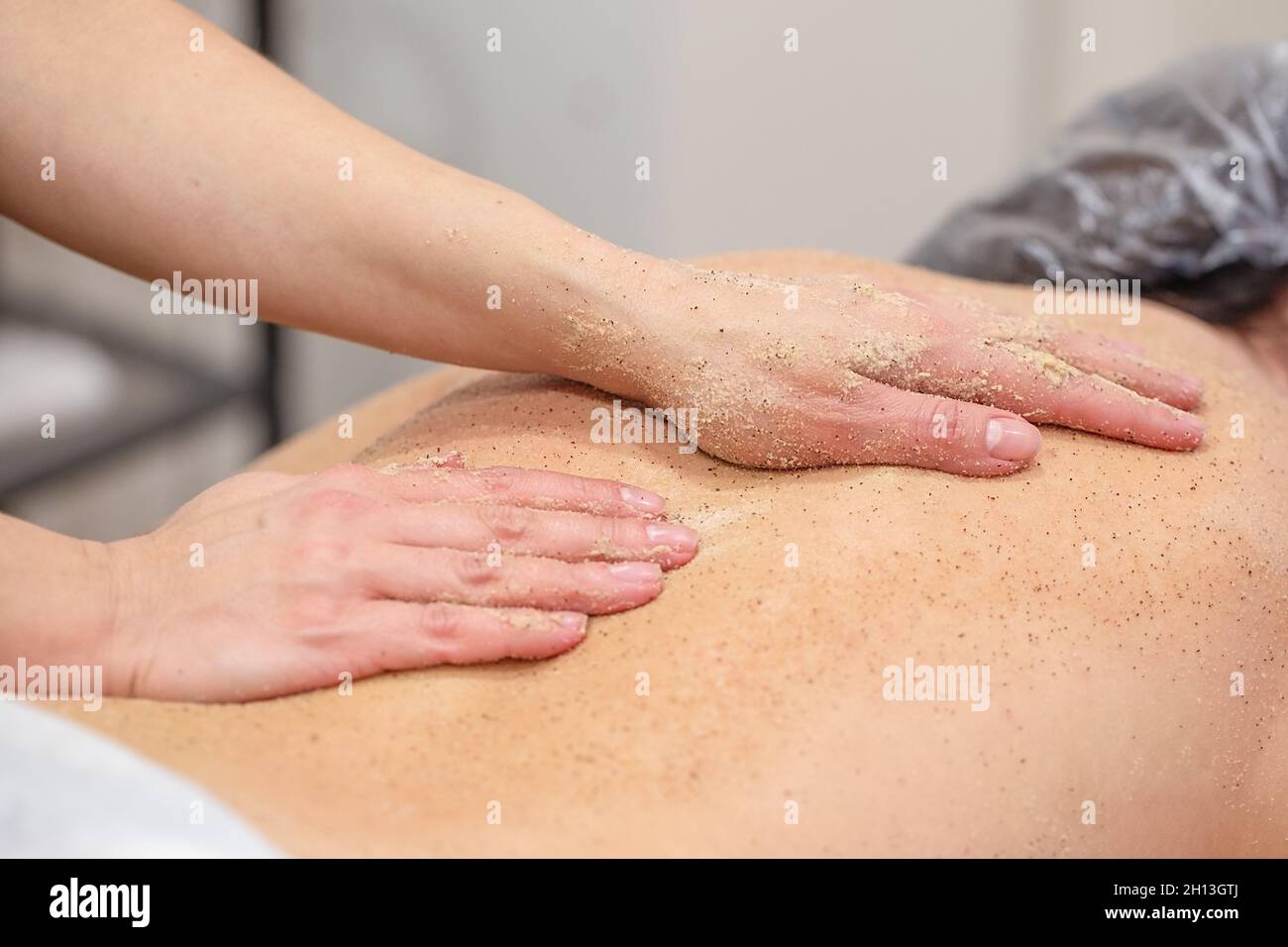 Die Hände des Massagisten schrubben dem Rücken der Frau Stockfoto