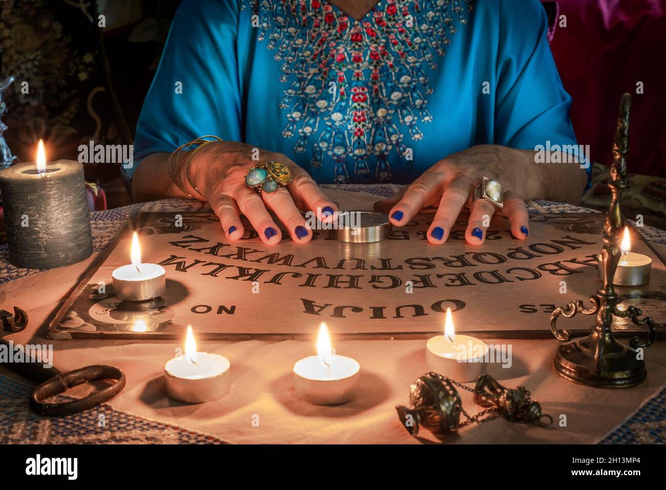 Ouija-Brett mit den Händen eines Wahrsager auf dem Tisch Stockfoto