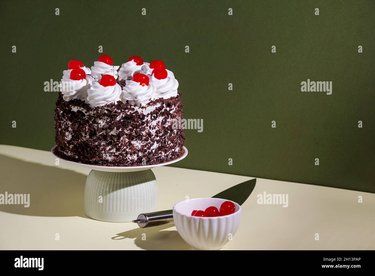 Schwarzwalder Kirschtorte, schwarzer Waldkuchen, raues Licht, Tischhintergrund im Sonnenlicht, modernes Stillleben, Kirschdessert auf modernem Hintergrund Stockfoto