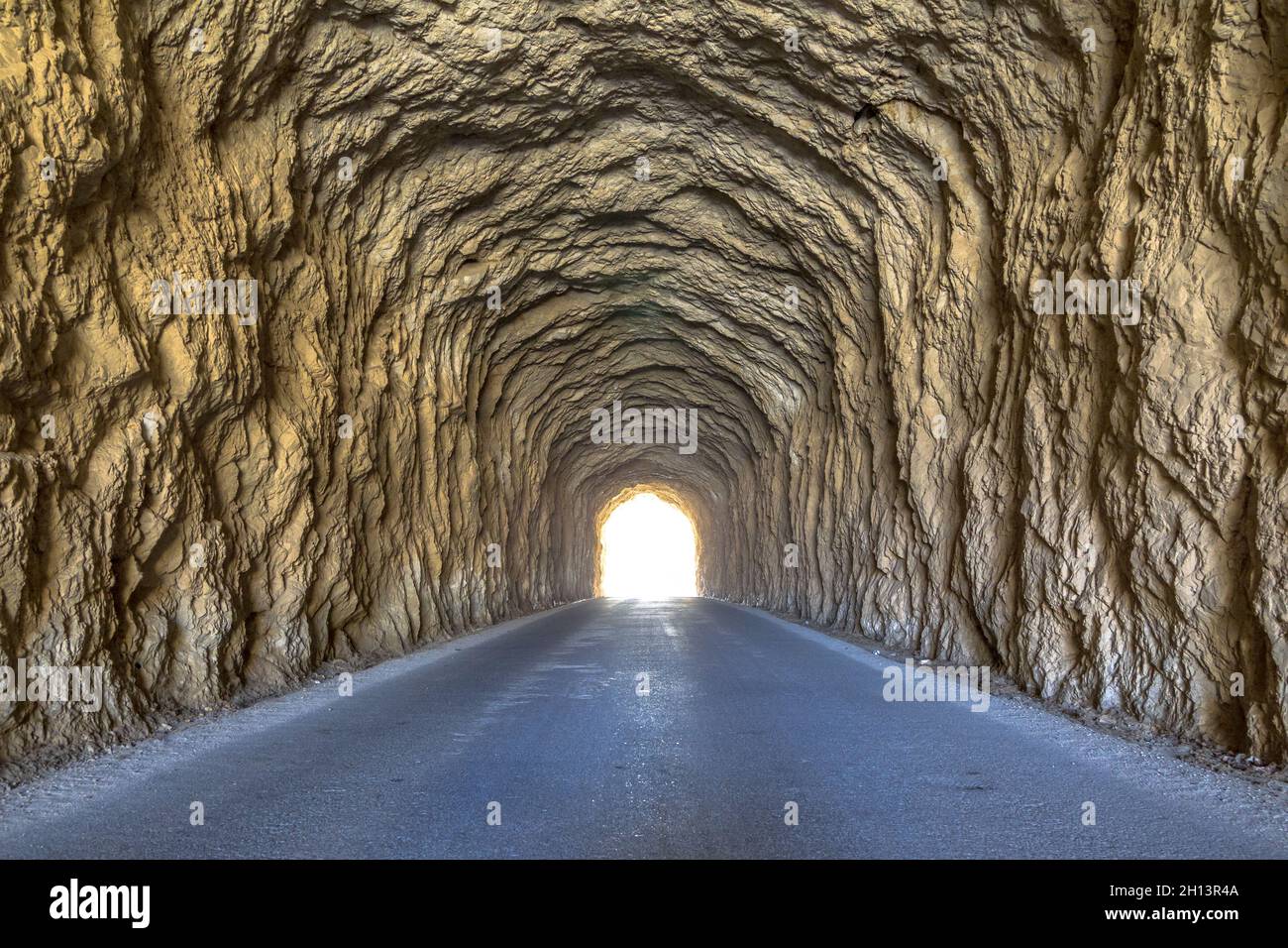 Helles Licht am Ende des Tunnels. Uralter Tunnel mit rauhen Wänden. Stockfoto