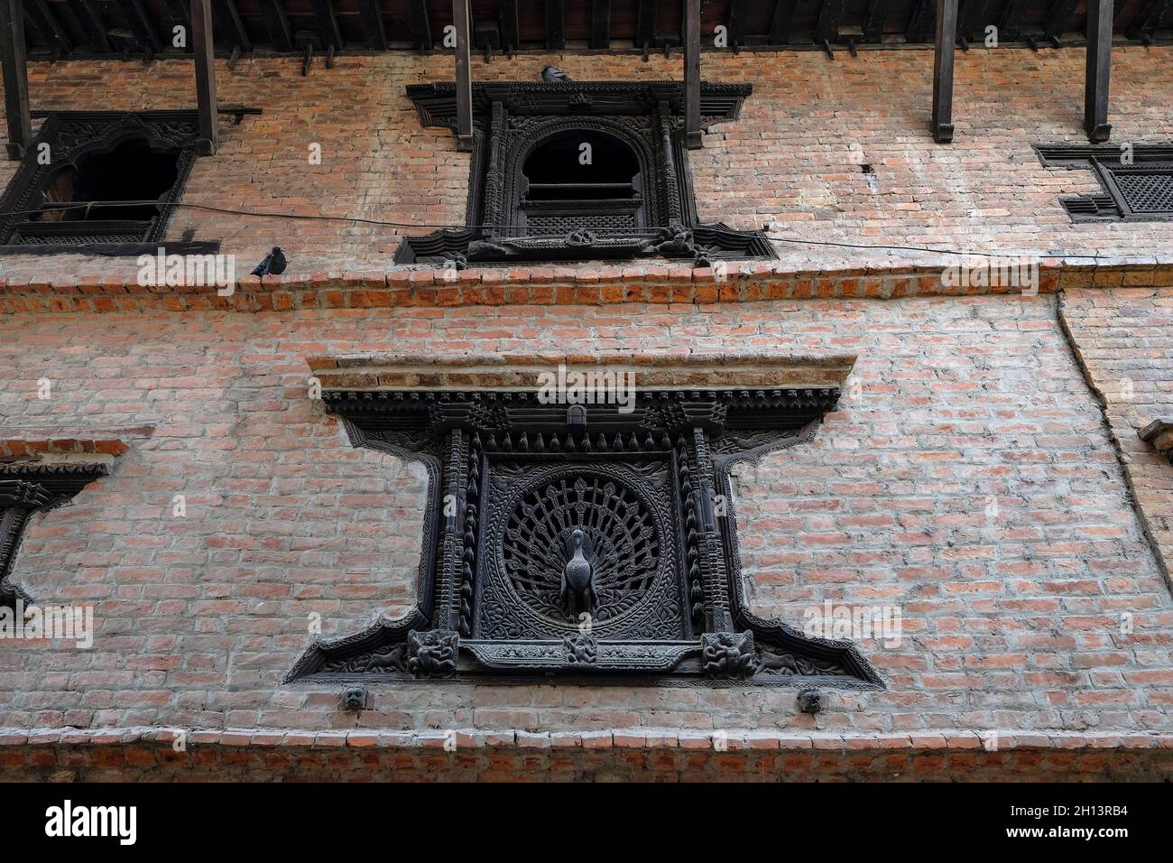 Das Pfauenfenster ist ein reich verzierte Holzfenster, die als Symbol der Newar-Kultur und -Kunst in Bhaktapur, Nepal, beschrieben wurden Stockfoto