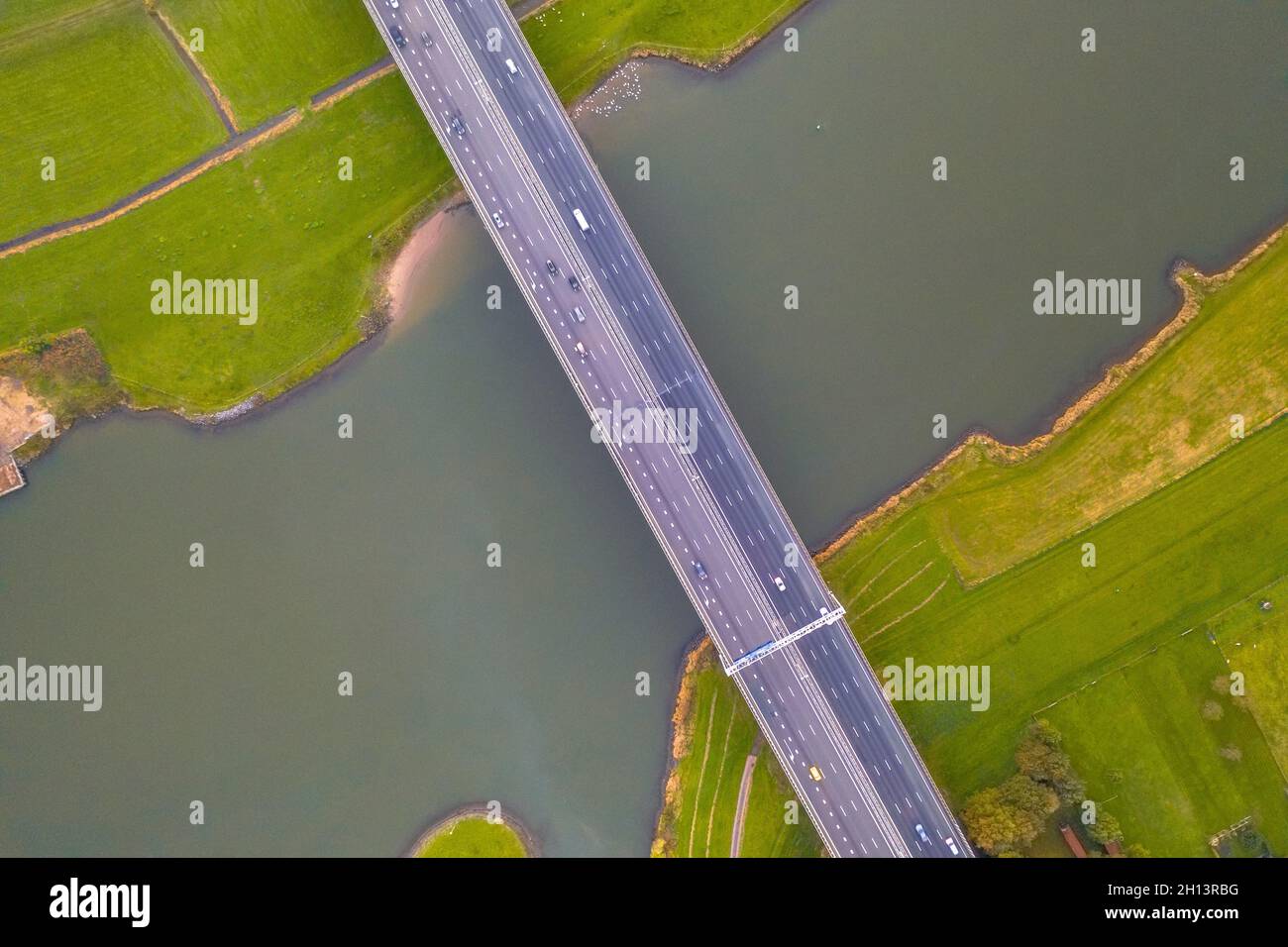 Luftaufnahme von oben nach unten von riesigen Flachland Fluss IJssel mit Autobahnbrücke durch landwirtschaftliche Landschaft. Zwolle, Overijssel Provinz, Niederlande. Dr Stockfoto