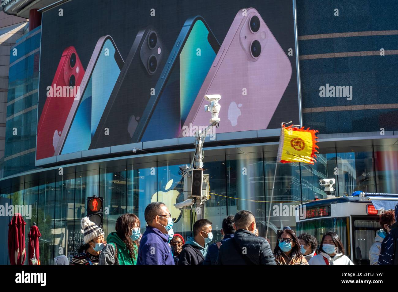 In Peking, China, laufen die Menschen an einem Apfelladen in Wangfujing vorbei, in dem die Werbung der iPhone 13-Serie auf einem großen Bildschirm erscheint. 16-Okt-2021 Stockfoto