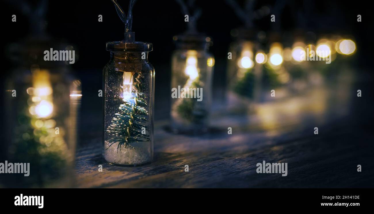 Weihnachtsdekoration elektrische Girlande mit kleinen Weihnachtsbaum innen warm getönte Lichter auf dem Holzbrett Tisch abgedeckt. Weihnachtliche Stimmung weit offen Stockfoto