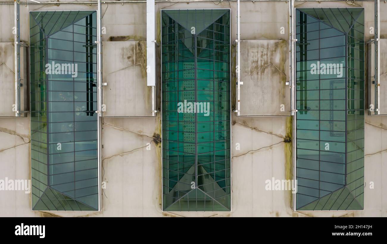 Von oben nach unten Nahaufnahme der modernen dreieckigen Dachfenster mit Dachfenster in grüner Farbe auf dem Dach eines Einkaufszentrums Stockfoto