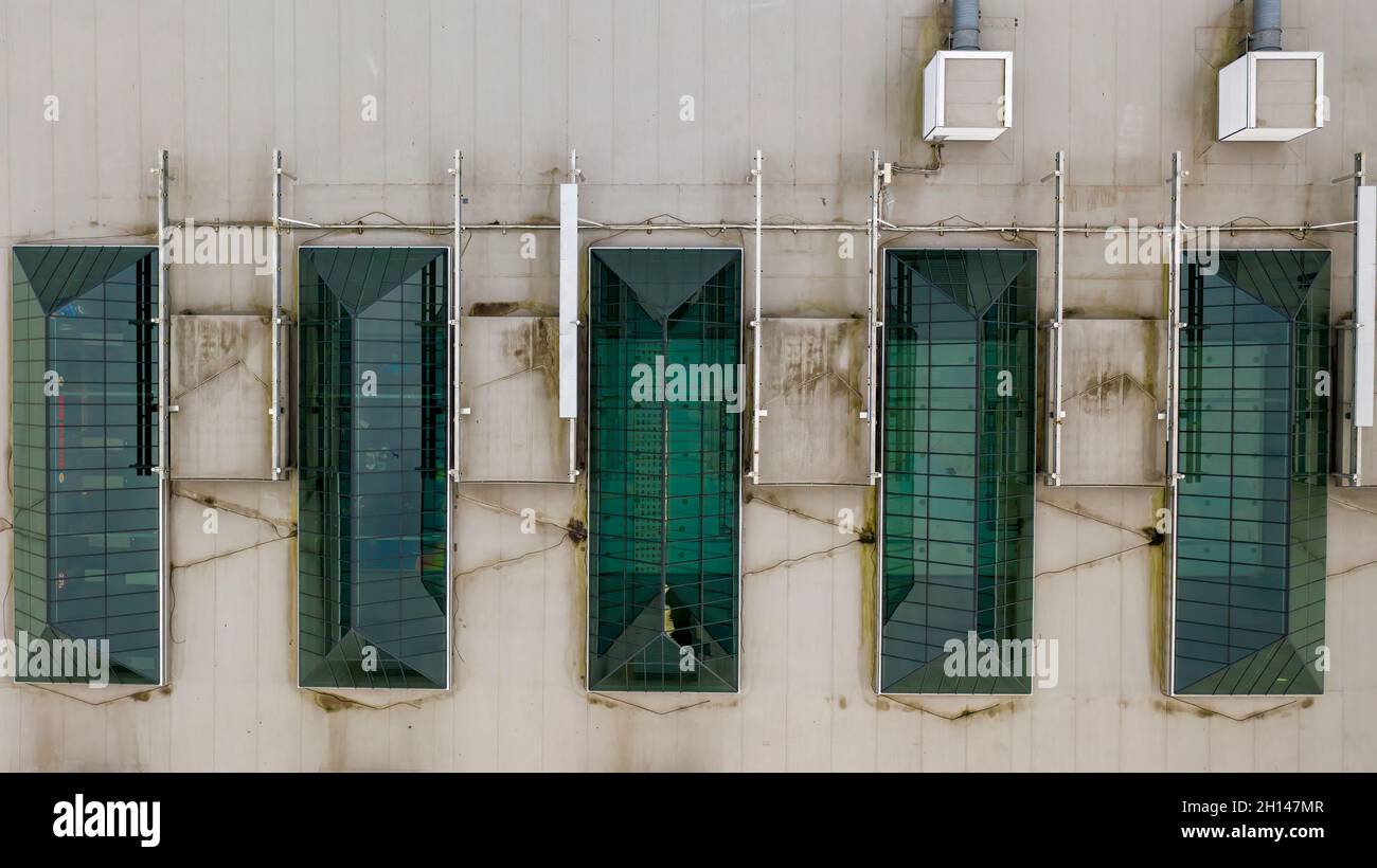 Blick von oben auf die modernen dreieckigen Dachfenster mit Dachfenster in grüner Farbe auf dem Dach eines Einkaufszentrums Stockfoto