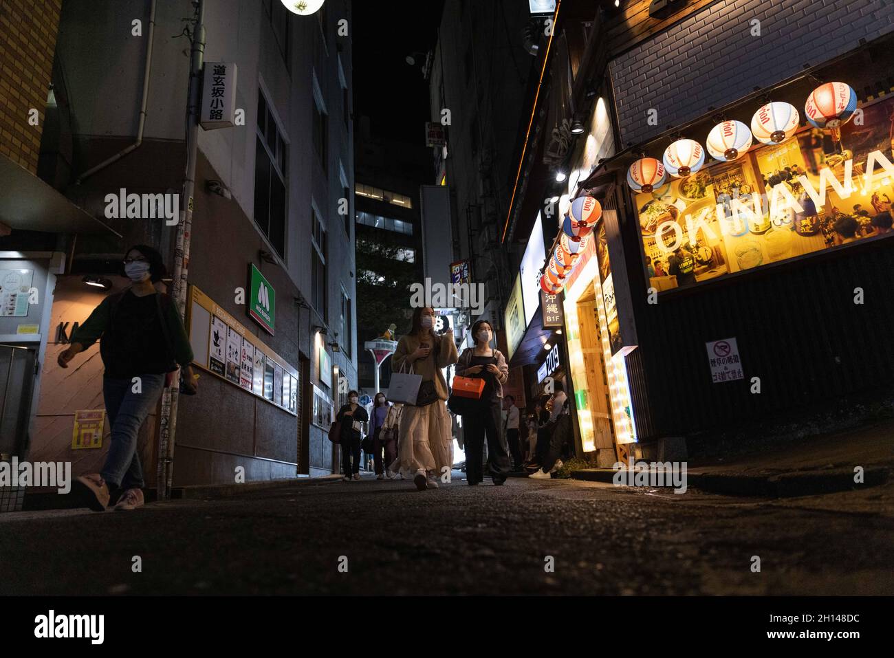 Maskierte Menschen gehen durch eine Gasse im Shibuya-Viertel in Tokio.das Nachtleben im Unterhaltungsviertel von Tokio Shibuya normalisiert sich wieder, nachdem der mit dem Coronavirus verbundene Ausnahmezustand in Tokio aufgehoben wurde. Restaurants und Bars können abends geöffnet sein und wieder Alkohol servieren. (Foto von Stanislav Kogiku / SOPA Images/Sipa USA) Stockfoto