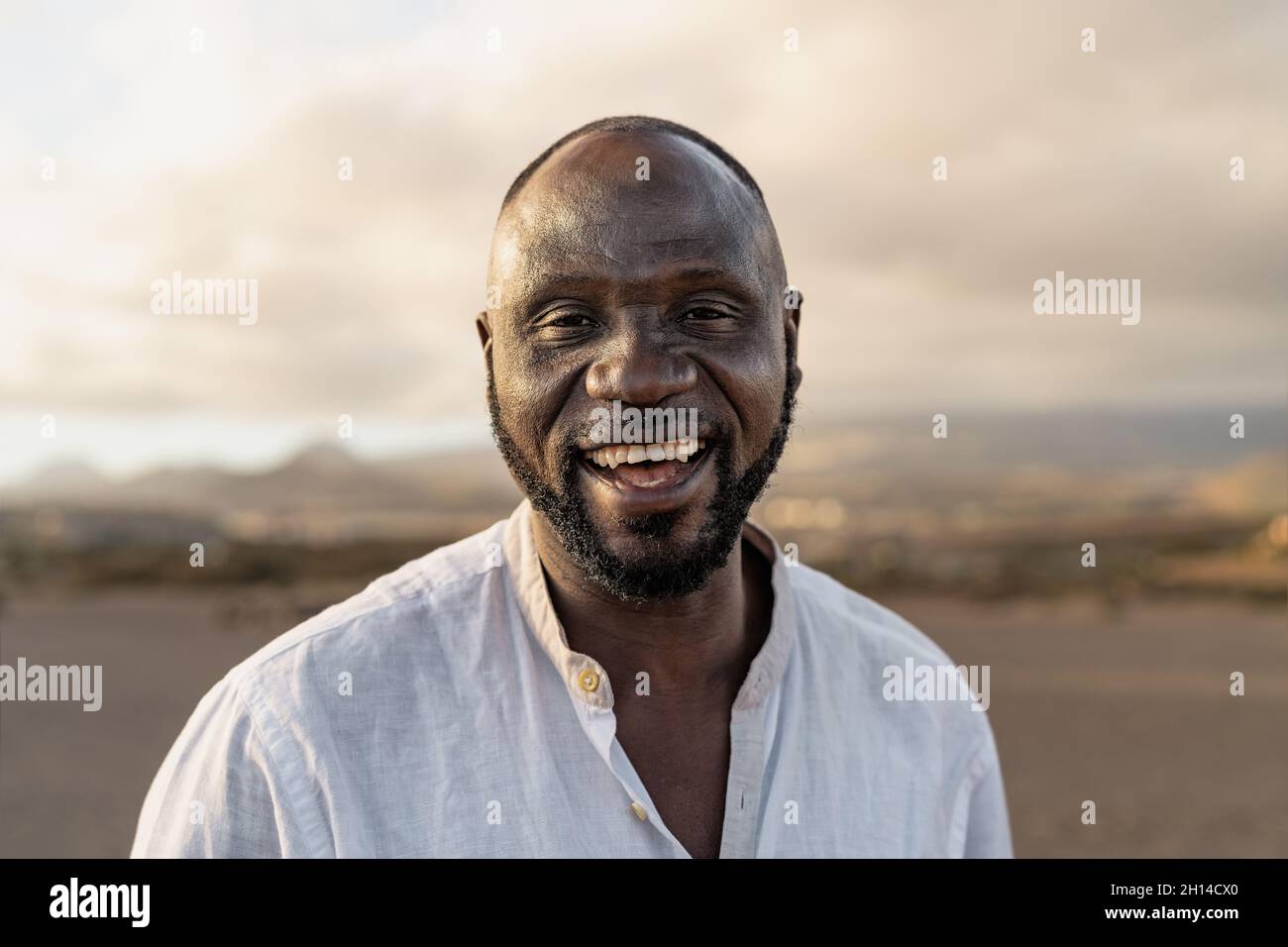Glücklicher afrikanischer Mann, der während der Sommerferien in der Kamera am Strand lächelt Stockfoto Glücklicher afrikanischer Mann, der während der Sommerferien in der Kamera am Strand lächelt Stockfoto