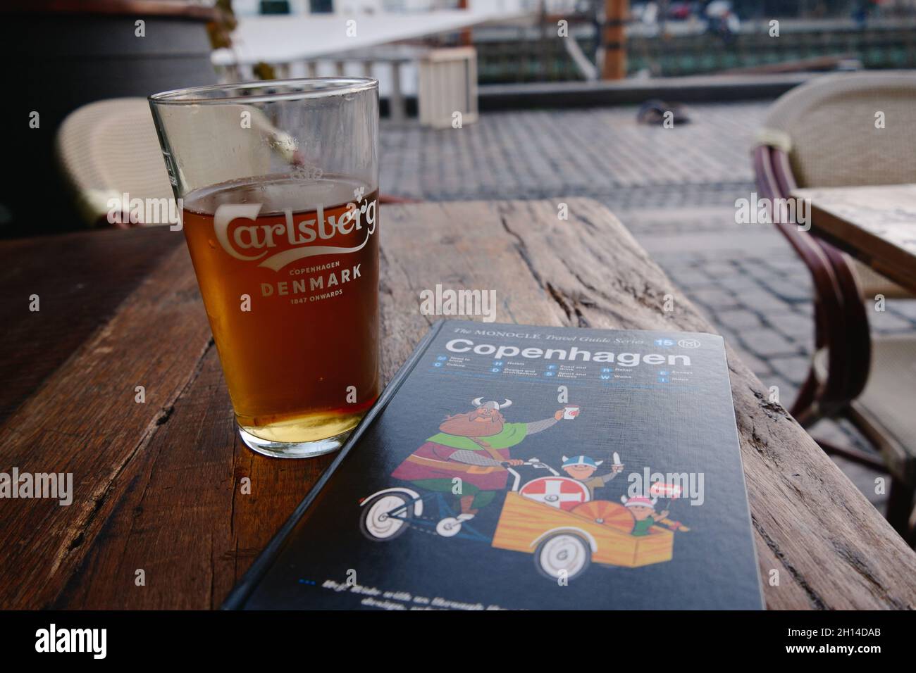 Ein Pint Carlsberg-Bier und der Monocle-Stadtführer für Kopenhagen an einem Restauranttisch in Nyhavn, Kopenhagen, Dänemark, Skandinavien, Oktober 2021 Stockfoto