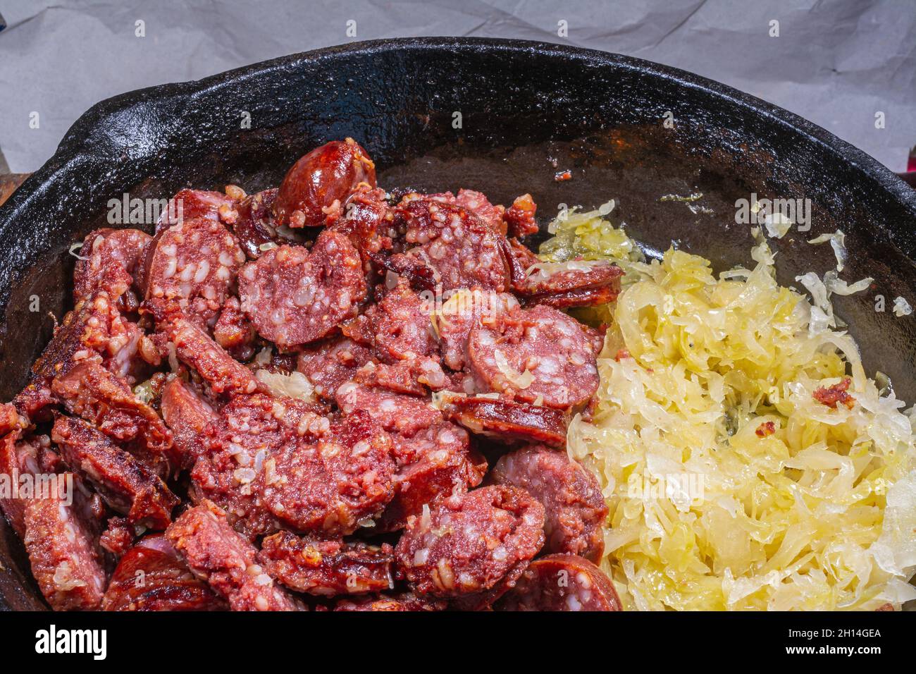 Gebratene Wurstscheiben mit Gerstenkörnern und Sauerkraut auf gusseiserner Bratpfanne Stockfoto