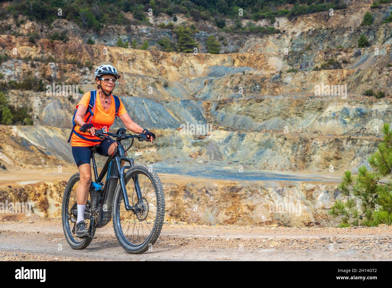 Nette aktive Frau, die ihr elektrisches Mountainbike in den verlassenen Eisenerzminen der Halbinsel Calamite auf der Insel Elba, Toskanischer Archipel, T reitet Stockfoto