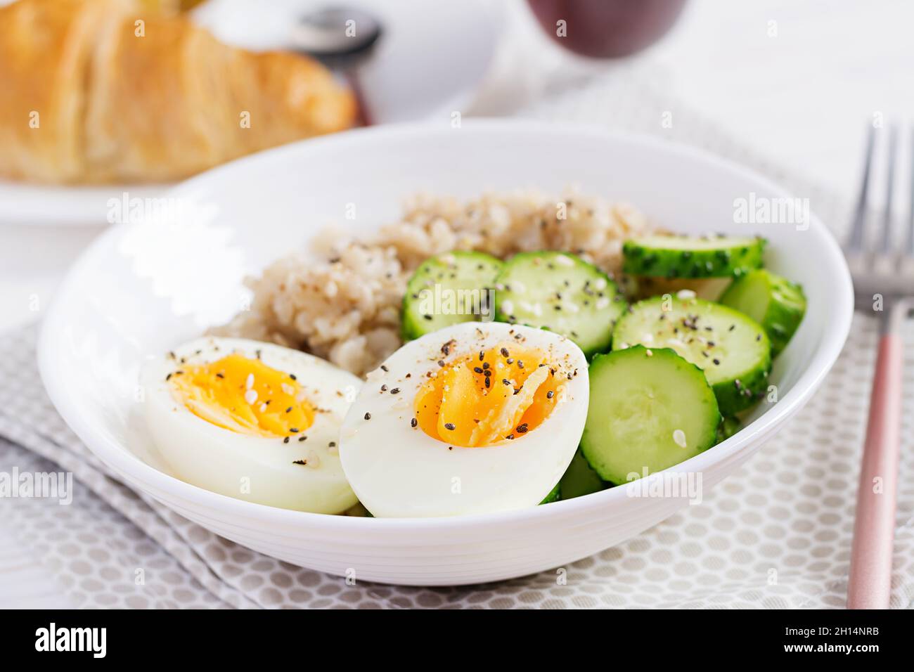 Frühstück Haferbrei mit gekochtem Ei, Gurke und Sesam. Gesunde, ausgewogene Ernährung. Stockfoto