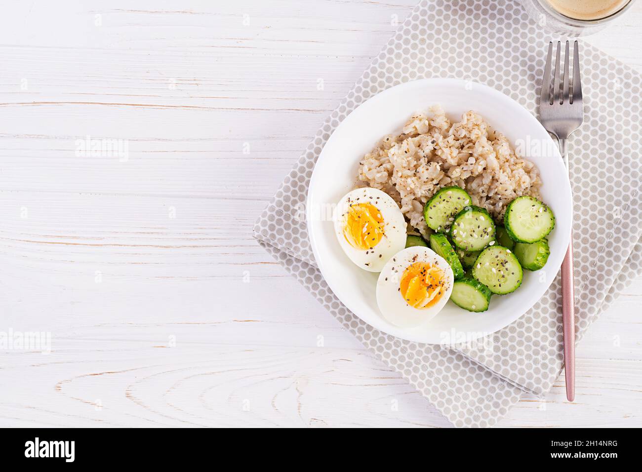 Frühstück Haferbrei mit gekochtem Ei, Gurke und Sesam. Gesunde, ausgewogene Ernährung. Draufsicht, flach liegend Stockfoto