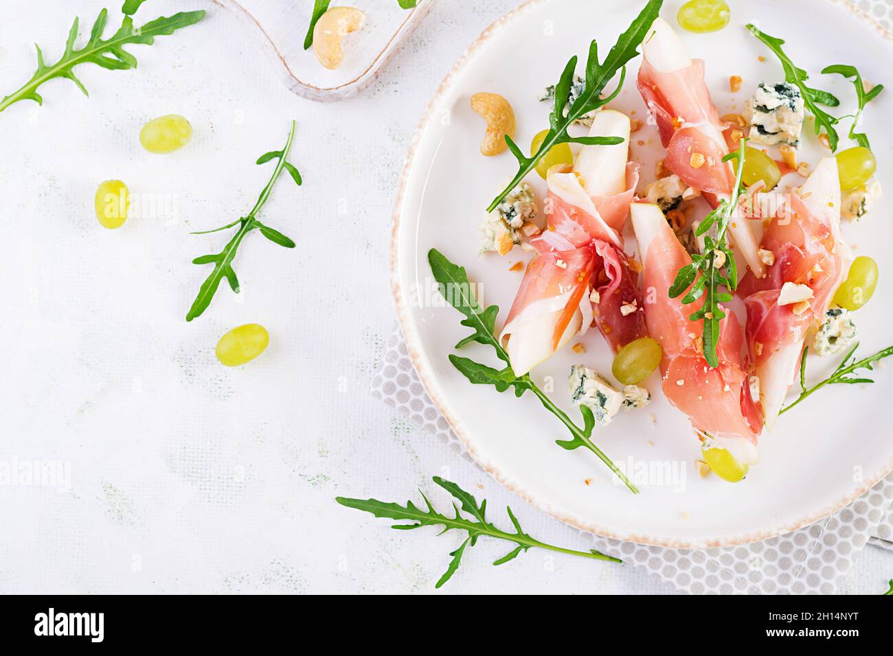 Vorspeise mit Birne, Blauschimmelkäse und Schinken für den Urlaub auf einem weißen Teller. Draufsicht, flach liegend Stockfoto