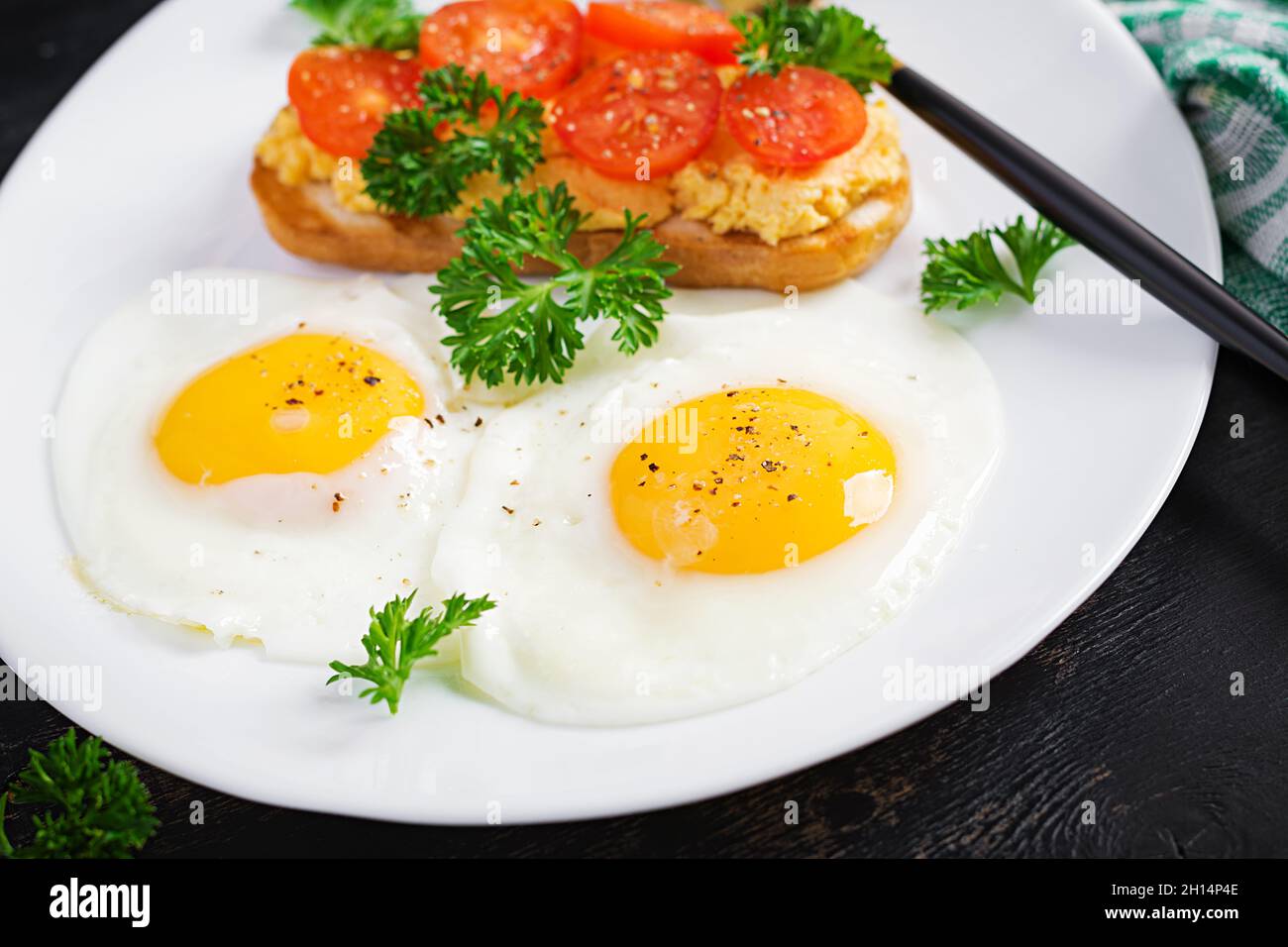 Spiegeleier und ein gegrilltes Hähnchenpastete-Sandwich auf dunklem Hintergrund. Stockfoto