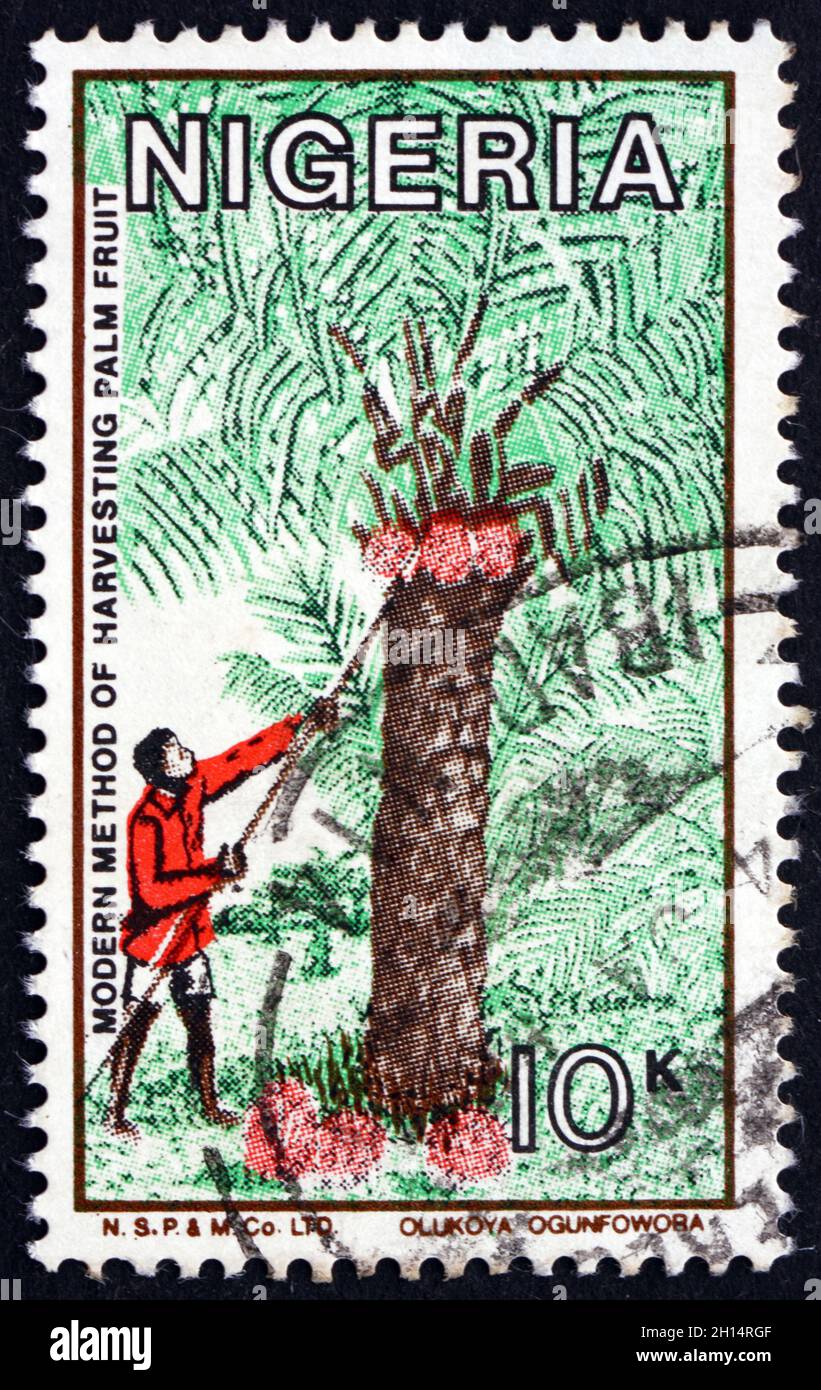 NIGERIA - UM 1986: Eine in Nigeria gedruckte Marke zeigt die moderne Methode der Palmfrucht-Ernte, um 1986 Stockfoto