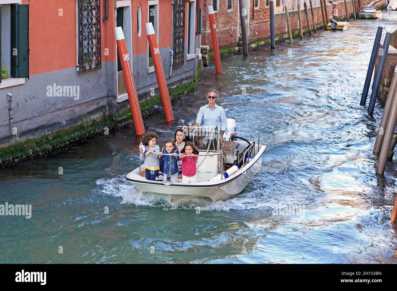 VENEDIG, ITALIEN - 18. MAI 2018: Eine unbekannte Familie spaziert mit dem Motorboot durch einen der Kanäle des Dorsoduro-Viertels. Stockfoto VENEDIG, ITALIEN - 18. MAI 2018: Eine unbekannte Familie spaziert mit dem Motorboot durch einen der Kanäle des Dorsoduro-Viertels. Stockfoto