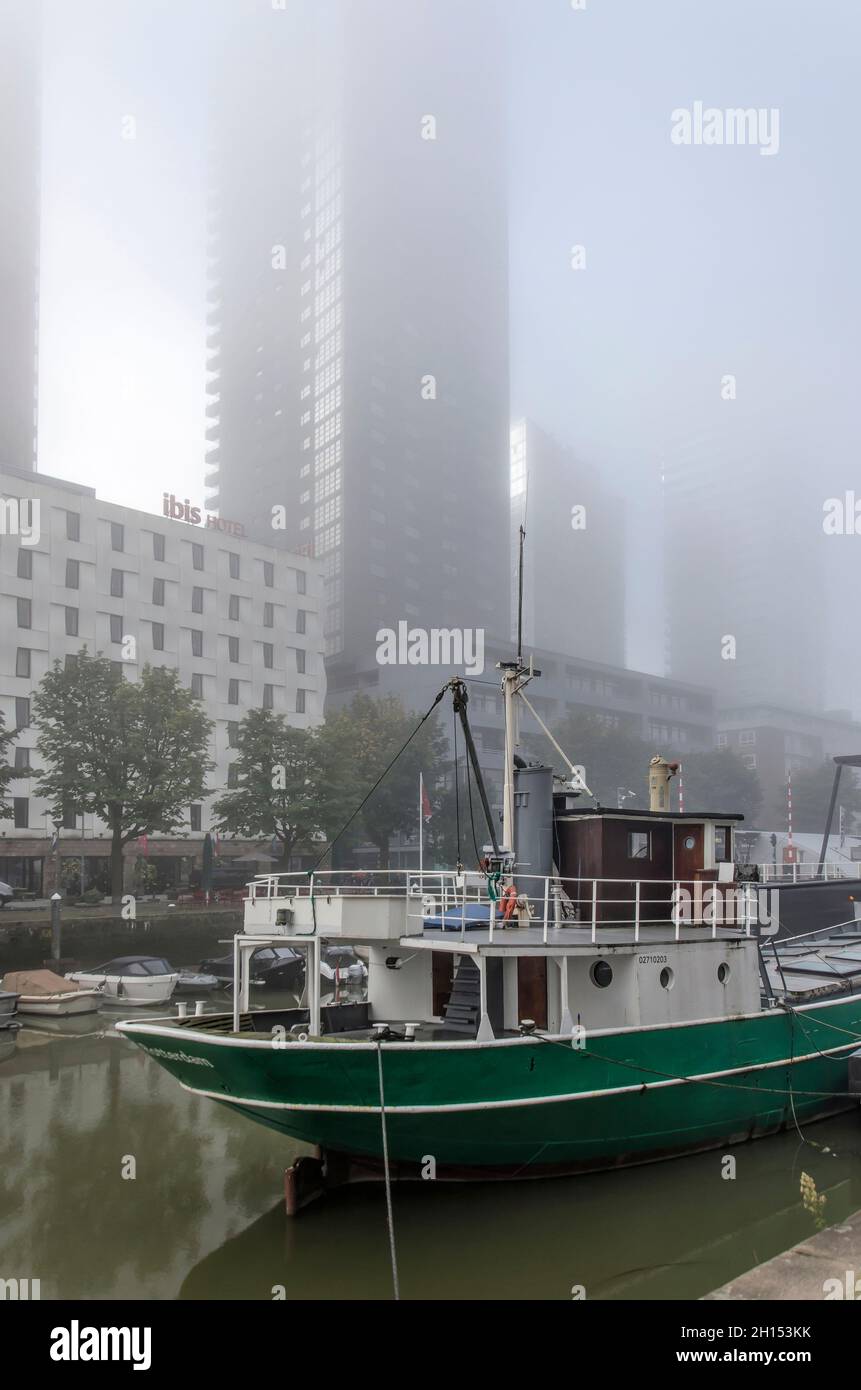 Rotterdam, Niederlande, 8. Oktober 2021: Historisches Schiff im Hafen von Wijnhaven mit dem Hintergrund moderner Wohntürme, die teilweise von MIS verdeckt sind Stockfoto