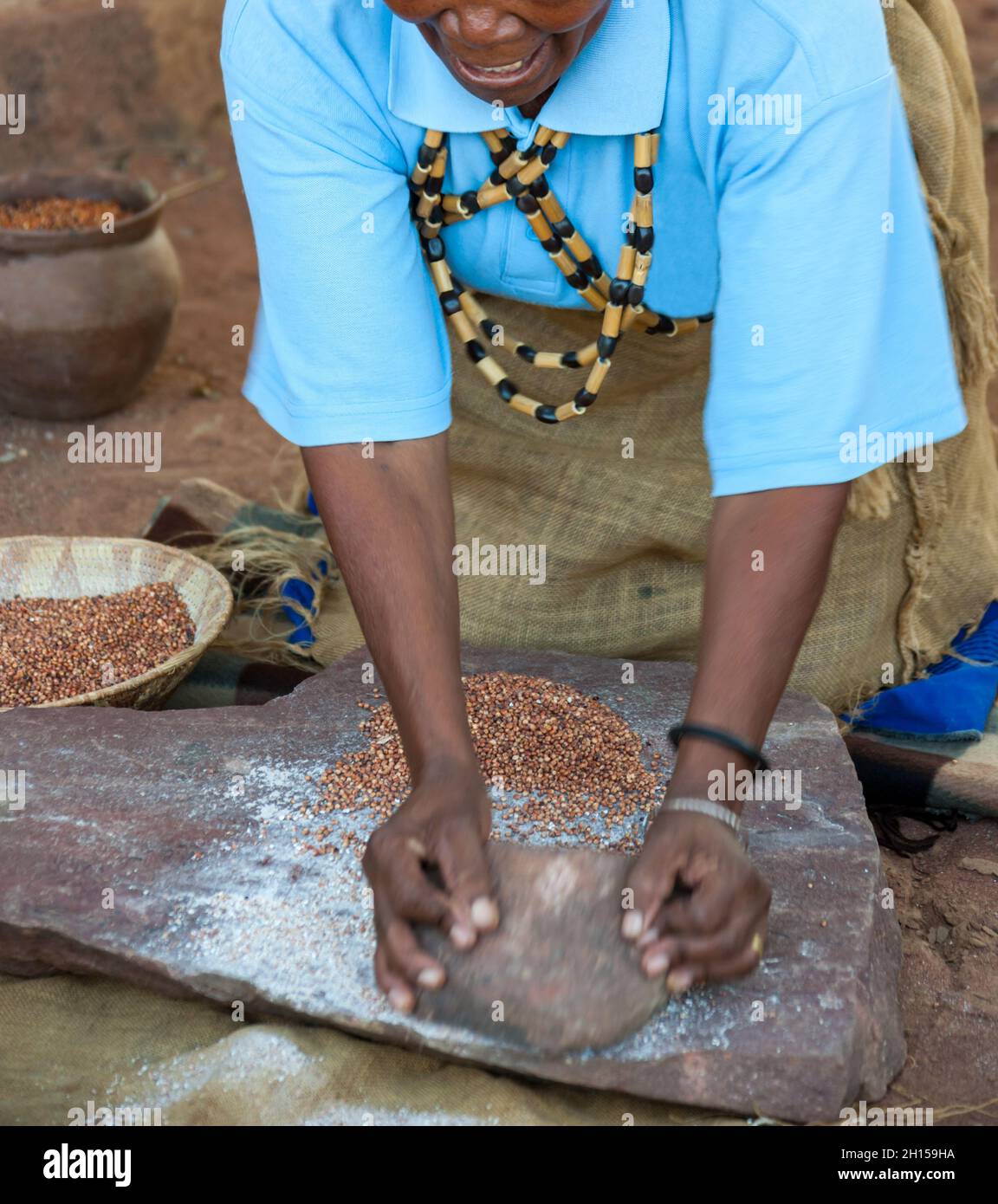 Alte Afrikanerin, die in Botswana auf traditionelle Weise Sorghum zerkleinert Stockfoto