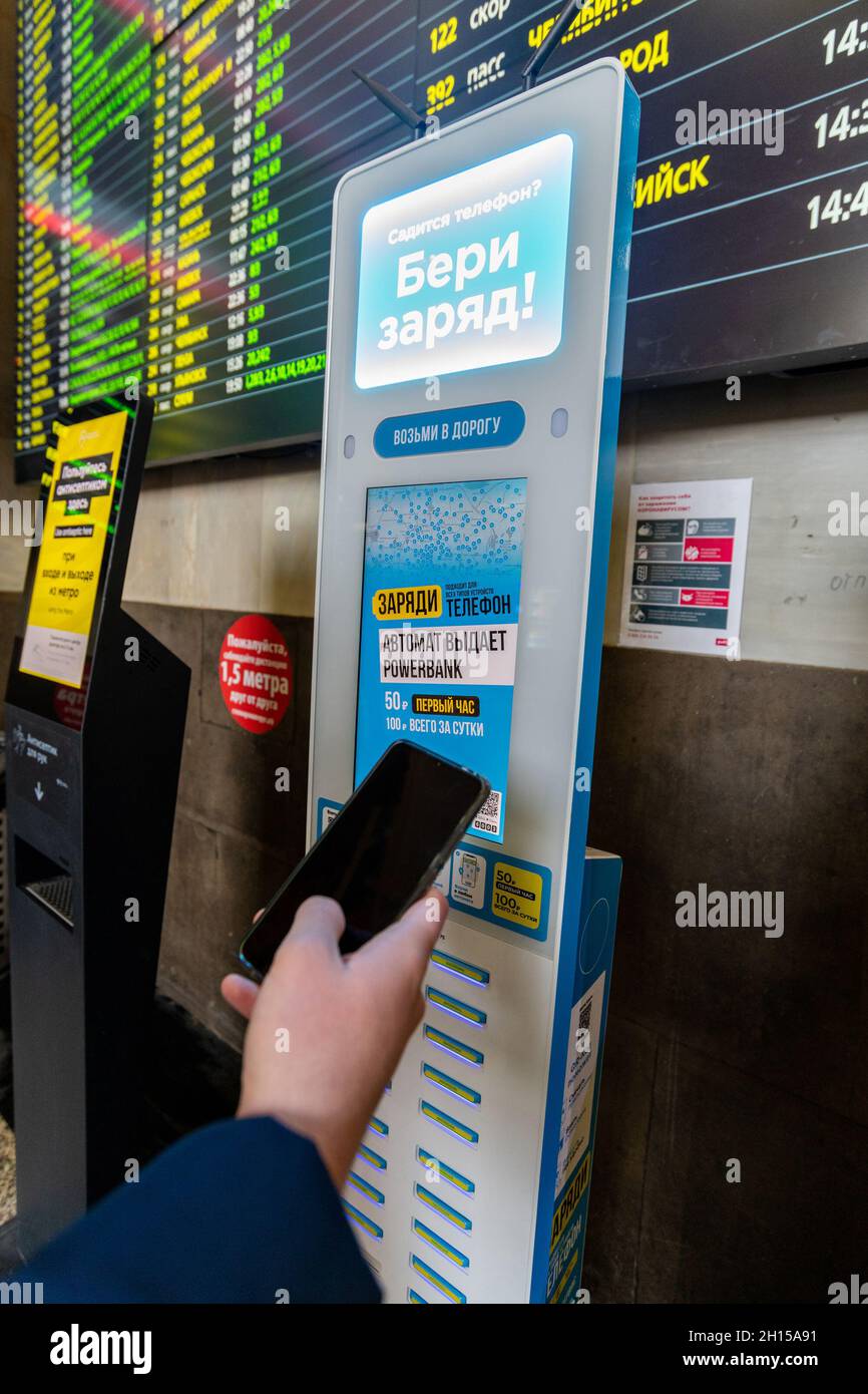 Moskau, Russland – 20. Februar. 20201. Hand mit einem Telefon auf dem Hintergrund des Ladegerätes mit Powerbank bei Kasansky Terminus Stockfoto