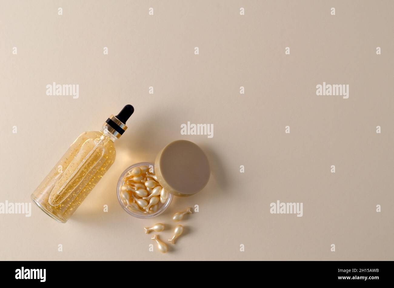 Verjüngende Creme Gesichts-Serum-Kapseln und Hyaluronserum in einer Flasche auf beigem Hintergrund, Hintergrund für die Demonstration von kosmetischen Produkten für Stockfoto