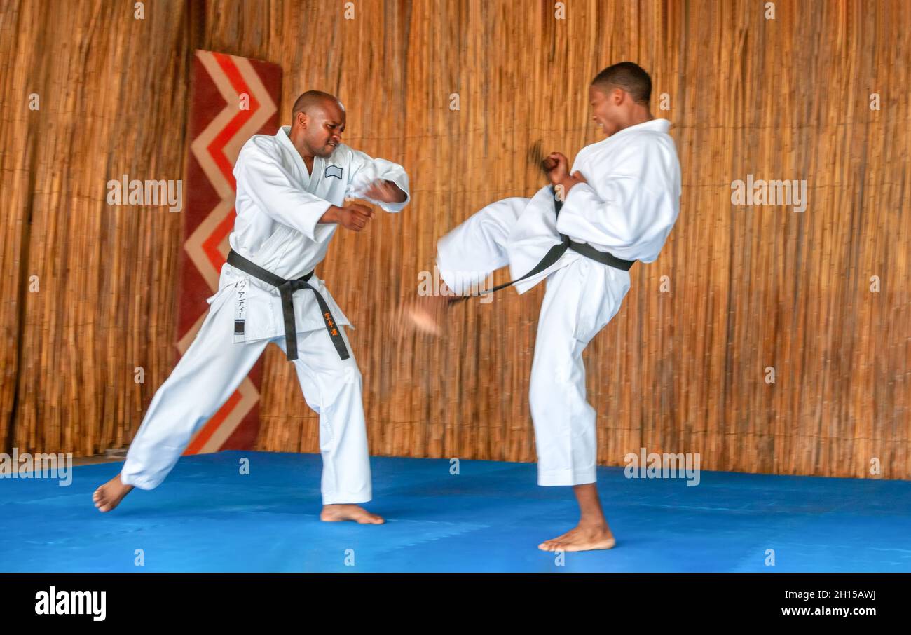 Afrikanische Männer, die Kumit an einem Dojo auf einem blauen Boden aufführen Stockfoto