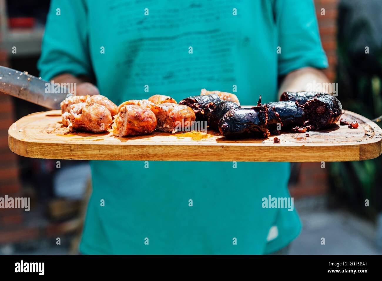 Argentinischer Steakhouse-Mann, der einen Tisch mit Chorizos ​​and Blutwurst zum Servieren trägt. Stockfoto
