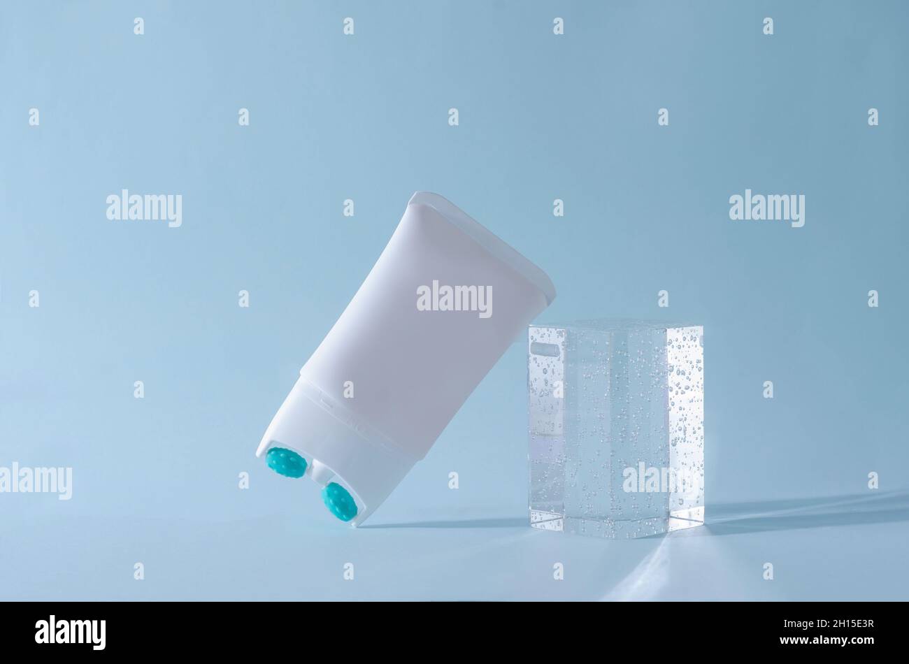 Creme-Lifting mit Massagedüse in einem weißen Rohr auf blauem Hintergrund mit einem Podium aus Plexiglas Stockfoto