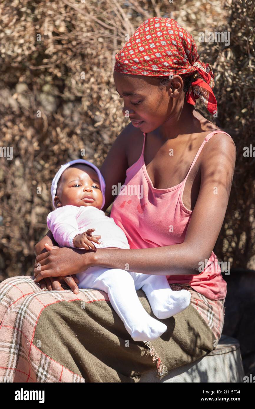 Alleinerziehende junge afrikanische Mutter in einem Dorf in Botswana, das Drama alleinerziehender Mütter aus der dritten Welt Stockfoto