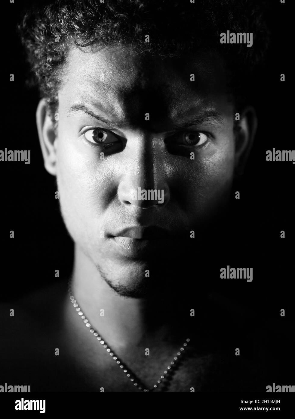 Porträt eines jungen kubaners mit gemischter Rasse und einem harten Look, raues Licht, bw Stockfoto