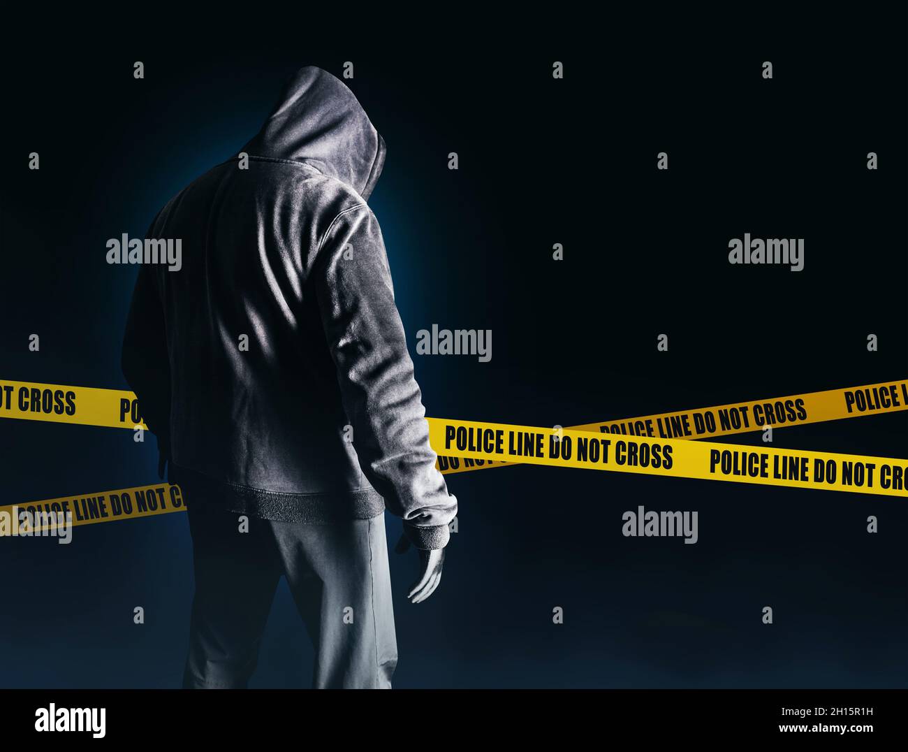Foto von gruseligen Horror fremden Stalker Mann in schwarzer Kapuze und Kleidung auf dunkelblauem Hintergrund mit Polizei Linien. Stockfoto