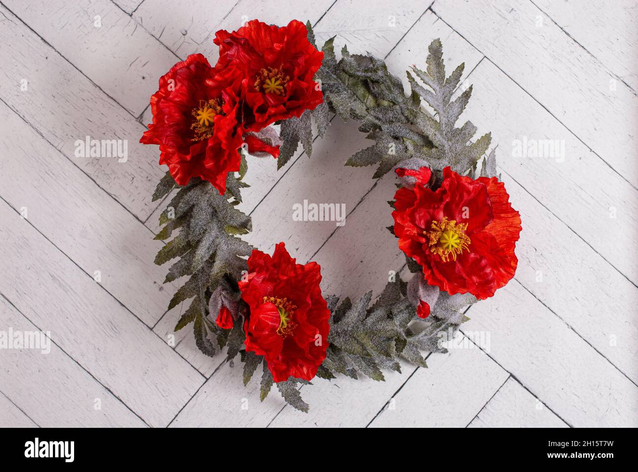 Ein Blumenkranz mit Mohnblumen an einer weißen Holzwand Stockfoto