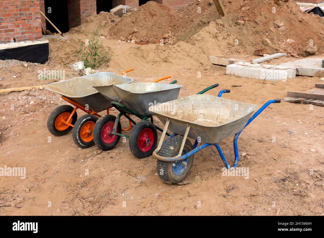 Bau Schubkarren. Drei Schubkarren ohne Menschen auf der Baustelle. Bauwerkzeug. Stockfoto
