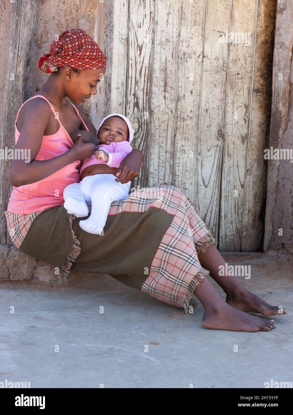 Alleinerziehende junge afrikanische Mutter in einem Dorf in Botswana, das Drama alleinerziehender Mütter aus der dritten Welt Stockfoto