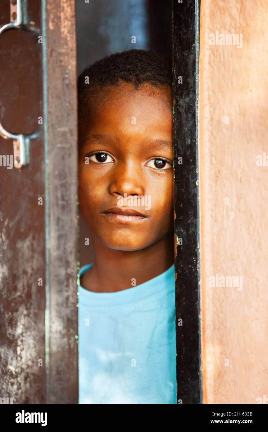 Armut afrikanisches Kinderdorf in Botswana, ländliche Gegend, spielen und sich vor der grünen Tür verstecken, Stockfoto