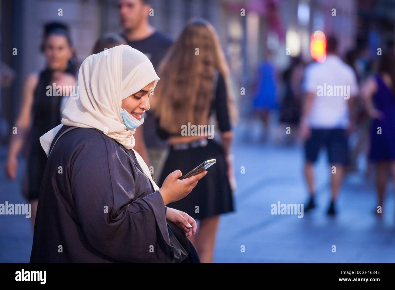 BELGRAD, SERBIEN - 22. JULI 2021: Junge arabische Frau aus dem Nahen Osten mit islamischem Schal-Schleier und Gesichtsmaske unter dem Kinn, während der covid 19 cor Stockfoto