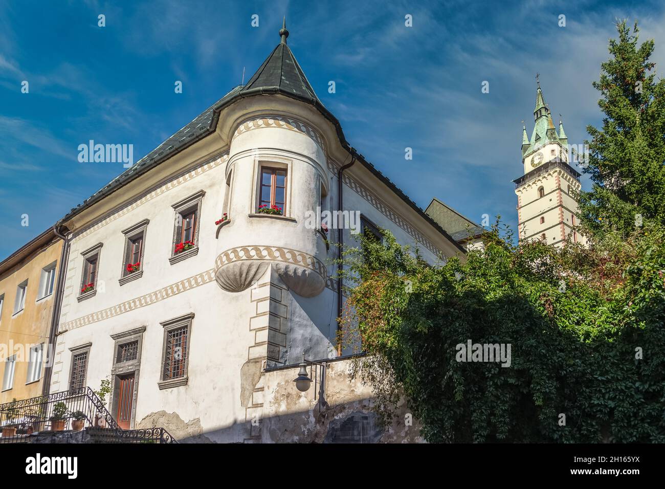 Renaissance-Herrenhaus in Kremnica mit turmähnlichen Turm in der Stadt aus Gold in der Slowakei mit imposanten Schlosskirche Glockenturm im Hintergrund Stockfoto