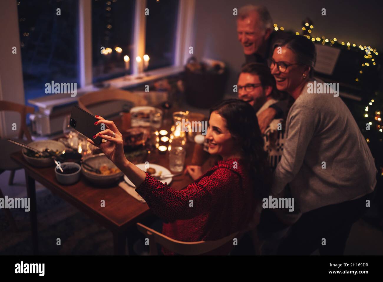 Europäische Familie spricht Selfie auf dem Handy während des Weihnachtsessens zu Hause. Konzentrieren Sie sich auf das Handy und die weibliche Hand, die Selfies macht. Stockfoto
