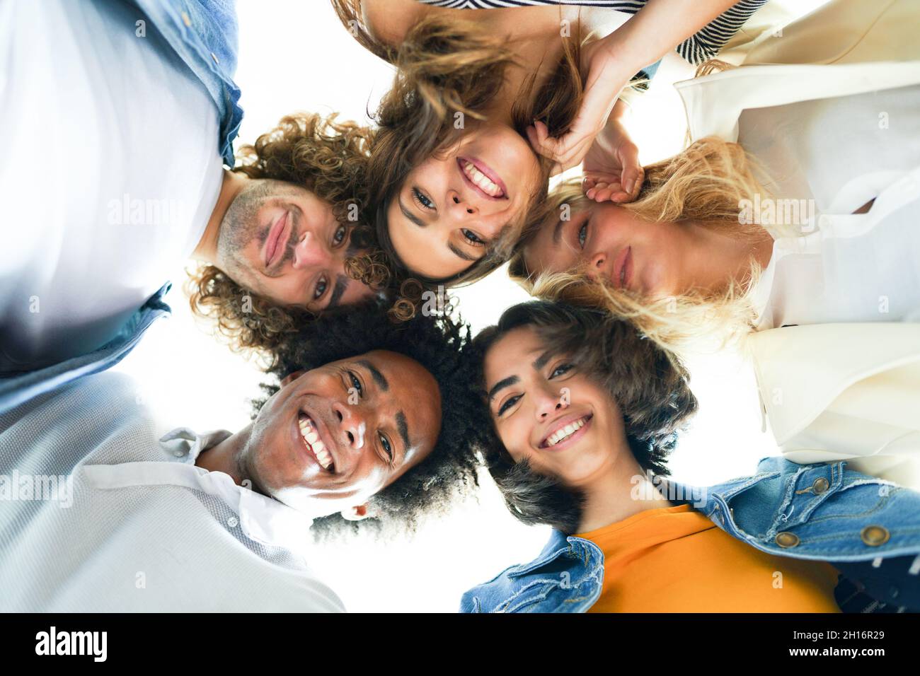 Multiethnische Gruppe von Freunden mit ihren Köpfen zusammen in einem Kreis. Stockfoto