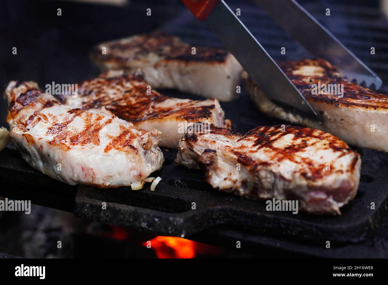 BBQ Grill Pit mit Glowing and Flaming Hot, Steaks, Food Background, Close-Up. Selektiver Fokus. Stockfoto