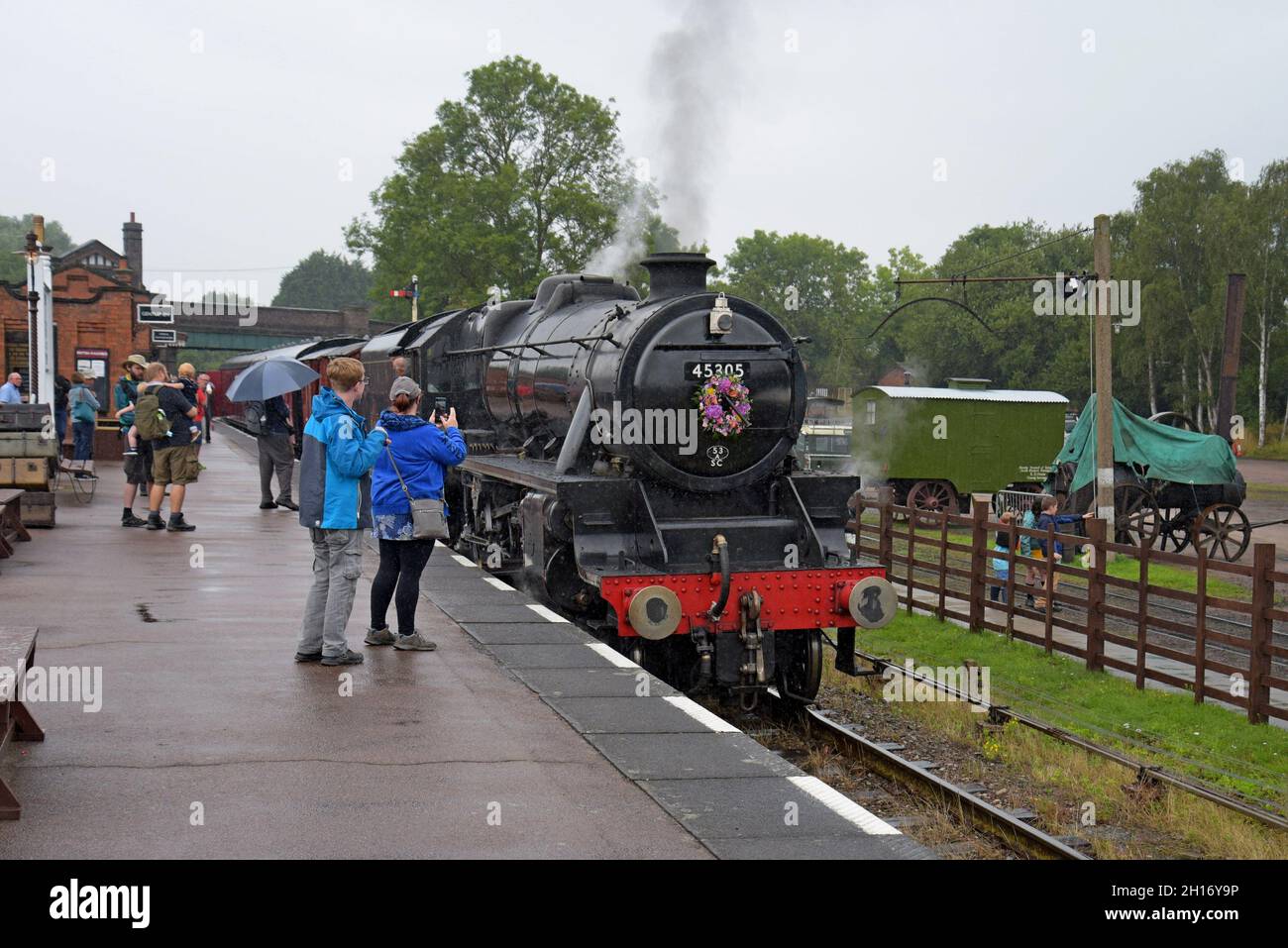 Eisenbahnliebhaber beobachten die ehemalige Dampflokomotive LMS 8F 48305 bei der Ankunft in Quorn & Woodhouse Statio bei der Great Central Heritage Railway, Leicestershire Stockfoto