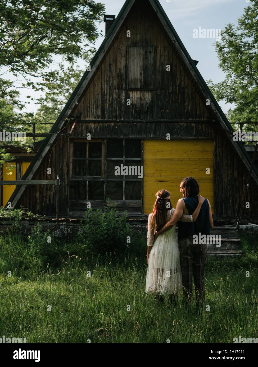 Rückansicht eines attraktiven Paares, das sich vor einem alten Holzhaus umarmt Stockfoto